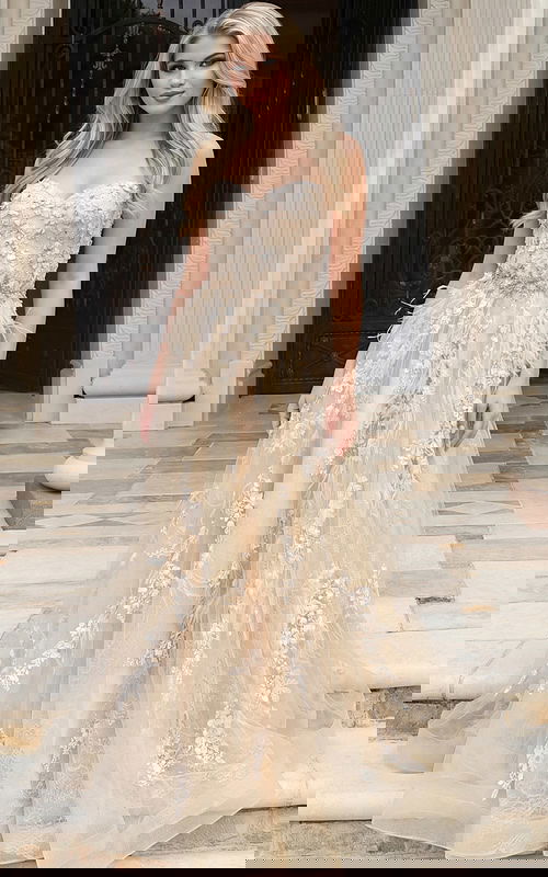 Front view of a strapless floral appliqué gown with layered tulle skirt